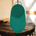 Bolso verde circular con flecos y asa dorada
